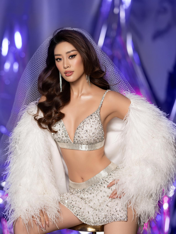 Người đẹp sinh năm 1995 diện set đồ váy ngắn kèm theo bra-top màu trắng đính đá lấp lánh. Phần trễ chữ V giúp Khánh Vân khoe được vẻ đẹp 'căng tràn' của vóc dáng, cô khoác thêm áo lông để tăng thêm độ sang chảnh cho tổng thể. 