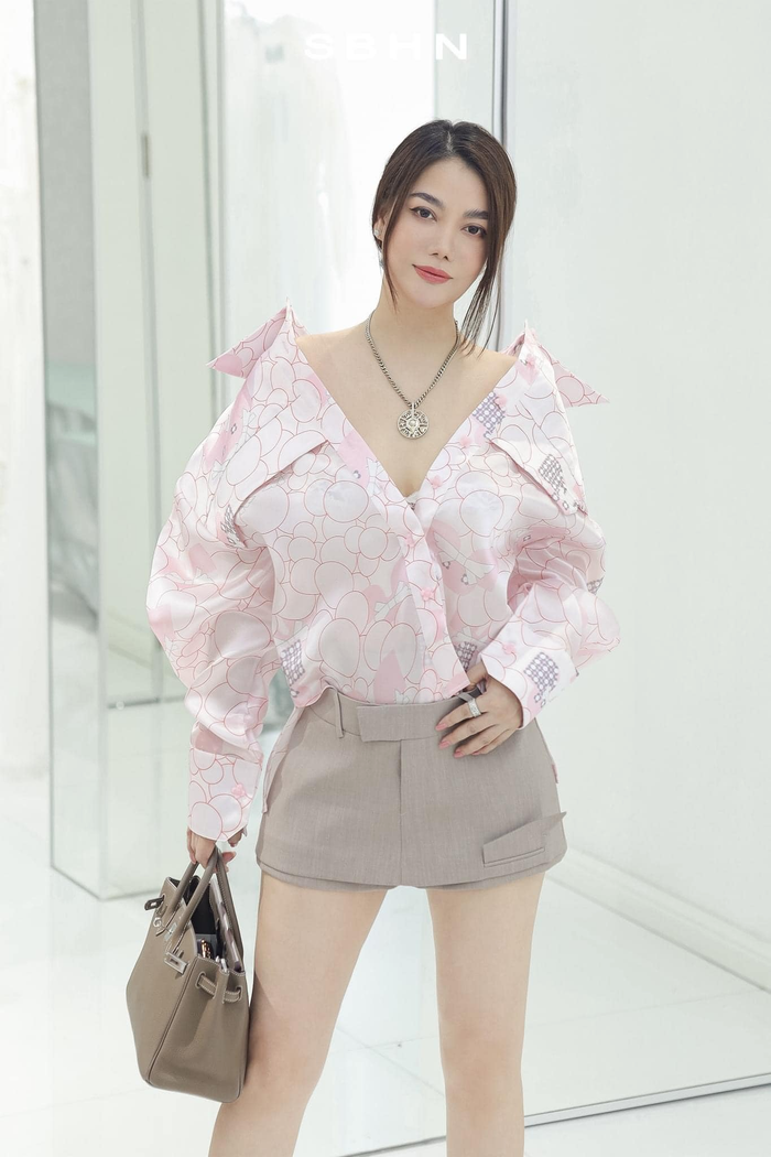 Không chỉ gói gọn với phong cách phụ nữ thành đạt, Trương Ngọc Ánh vẫn có những khoảnh khắc trẻ trung với gam màu sáng. Trong ảnh, chân dài Hà Nội mặc mẫu áo sơ mi oversize được sơ vin bên trong mẫu váy ngắn màu xám. Để tăng độ sang trọng, cô nàng mang thêm túi Hermes Birkin trăm triệu. 