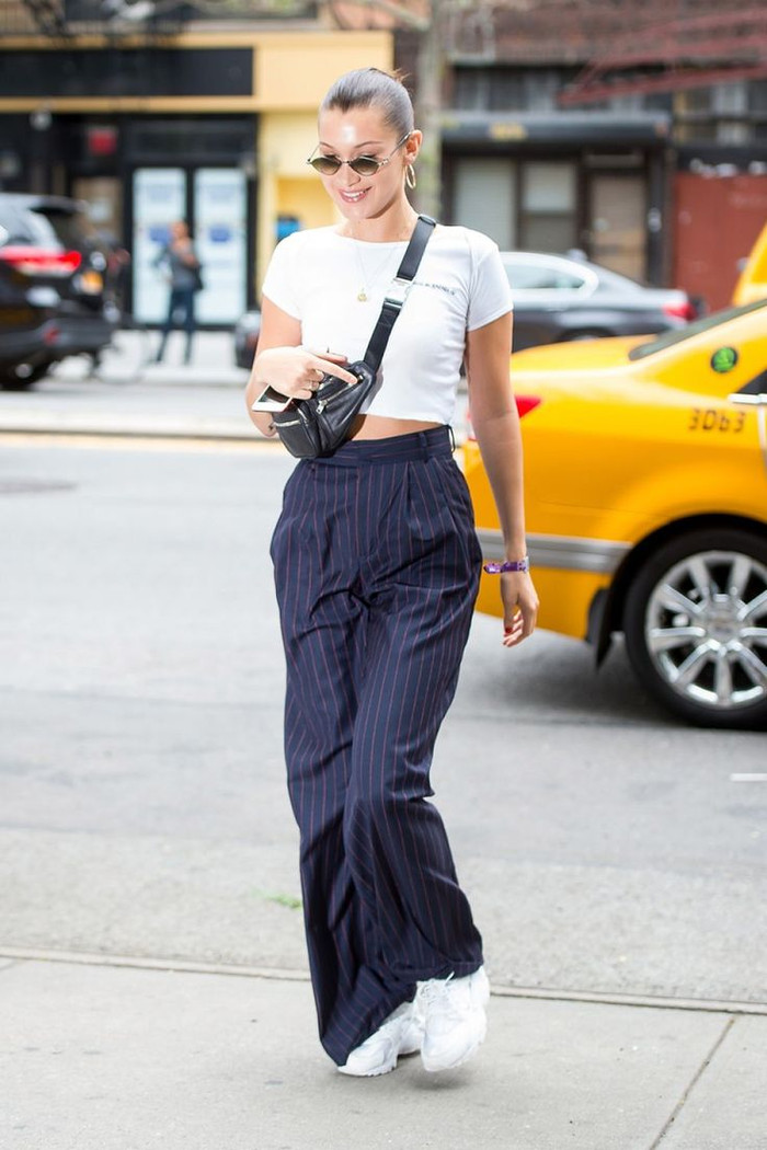 Nếu bạn muốn thử họa tiết mà vẫn giữ được sự tối giản, quần kẻ sọc là lựa chọn lý tưởng. Bella Hadid phối quần ống rộng xếp ly với áo liền quần bó sát, thêm thắt lưng bản to để tăng chiều sâu. Một chiếc áo khoác da quá khổ giúp hoàn thiện vẻ ngoài, vừa giữ ấm vừa tạo cá tính. 