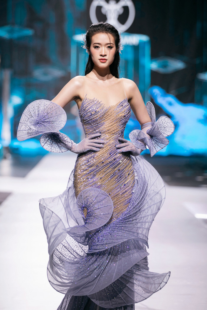 Bộ sưu tập “Undersea” của NTK Nguyễn Minh Tuấn đưa khán giả lạc vào thế giới huyền bí dưới lòng đại dương. Những thiết kế lấp lánh pha lê Swarovski, kỹ thuật in 3D, dựng gọng và draping tinh xảo đã tái hiện những gợn sóng biển ngay trên sàn diễn. Từng chi tiết được chế tác thủ công tỉ mỉ trong nhiều tháng, mang đến vẻ đẹp sắc sảo và sang trọng. 