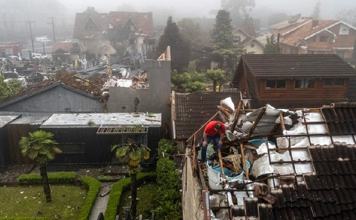 Người đàn ông kiểm tra mái nhà bị hư hại bởi chiếc máy bay gặp nạn.