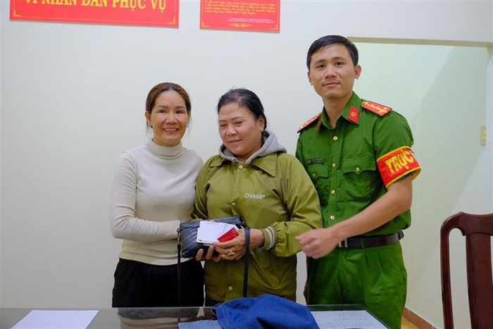 Chị Ngân (áo trắng) trao trả chiếc túi do chị Liên bỏ quên trước sự chứng kiến của cán bộ Công an Phường 1 - TP Bảo Lộc. Ảnh: Cổng thông tin điện tử Bộ Công an