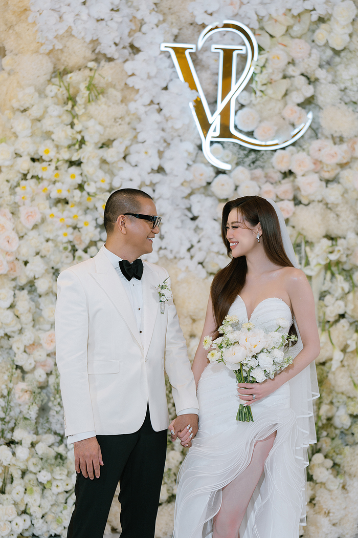 Người khóa sổ danh sách đám cưới trong năm 2024 của làng giải trí là Hoa hậu Khánh Vân và ông xã Nguyễn Long. Ở khoảnh khắc đón khách mời, Hoa hậu Khánh Vân được Lê Thanh Hòa thiết kế riêng váy lấy cảm hứng từ những gợn sóng mềm mại nhưng mạnh mẽ, chiếc váy cưới tôn vinh vẻ đẹp thuần khiết và lãng mạn của cô dâu. Điểm nhấn đầu tiên là phần cổ sweetheart neck yêu kiều, như một lời thì thầm ngọt ngào, kết hợp hoàn hảo với những chi tiết đính kết đá Swarovski tinh xảo ở phần thân váy, làm sáng bừng mọi khoảnh khắc.