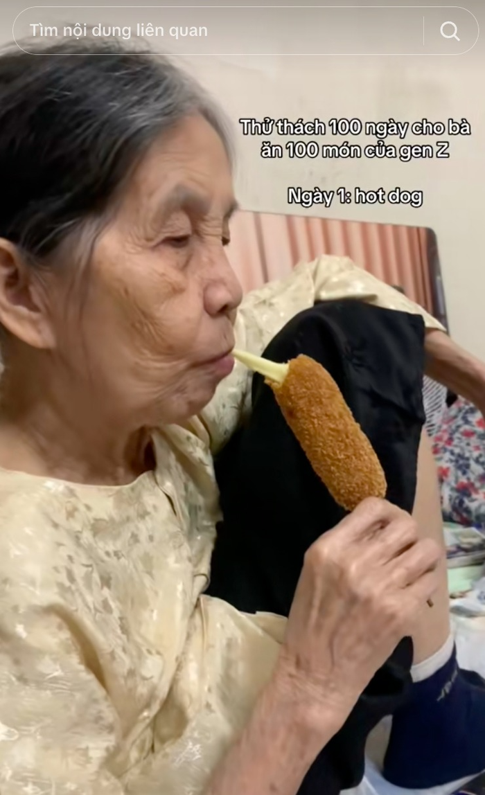 Bà ngoại vui vẻ thưởng thức chiếc hotdog trong ngày đầu tiên của chuỗi clip. Ảnh: @ancungbangoai
