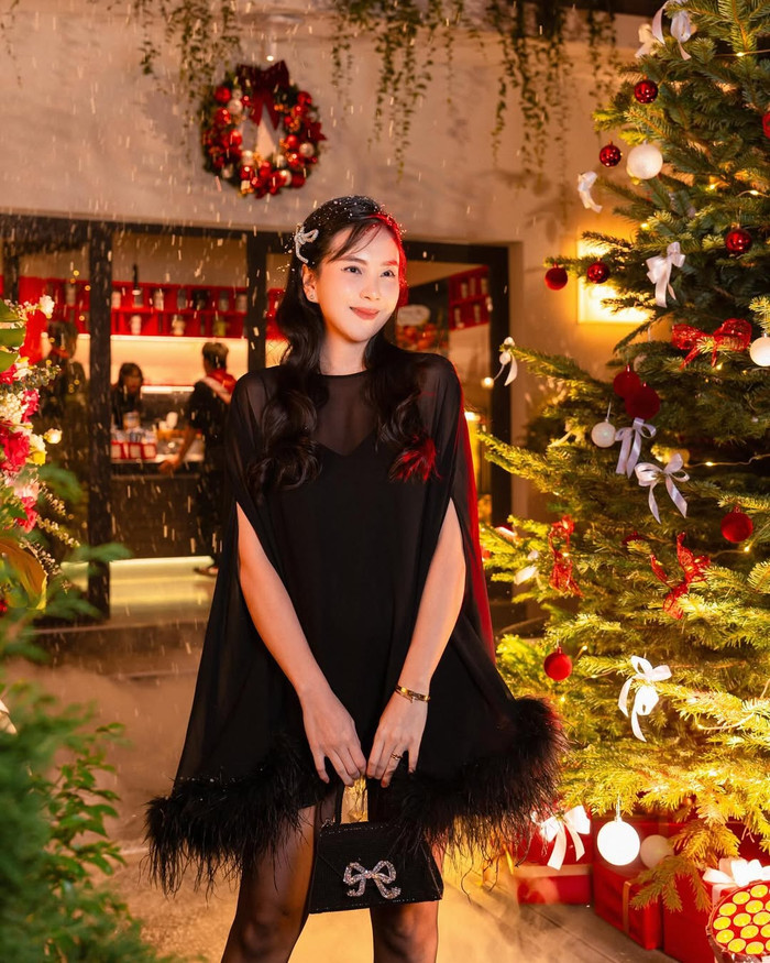 Trong khoảng thời gian này, MC Mai Ngọc bất ngờ chuyển hướng phong cách thời trang. Cô ưa chuộng những mẫu váy rộng, giấu nhẹm đi vóc dáng. Thời điểm xuống phố dạo chơi, MC Mai Ngọc khoác lên người thiết kế váy màu đen, form dáng xoè rộng. Item này còn được tạo điểm nhấn bởi phần đính kết lông vũ. Về phụ kiện, MC Mai Ngọc phối cùng chiếc túi xách đồng màu với trang phục. (Ảnh: FBNV)