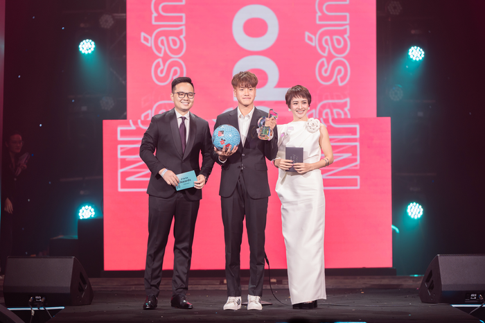 Chàng trai trẻ tự vỡ òa cầm trên tay chiếc cúp cùng trái bóng tròn.