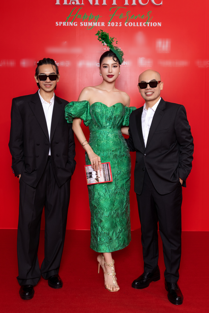 Á hậu Hoàng Nhung thân thiết bên cạnh hai nhà thiết kế Vũ Ngọc & Son. Chân dài sinh năm 1996 hóa quý cô cổ điển với váy bút chì trễ vai kết hợp chiếc mũ tiệc trà. 