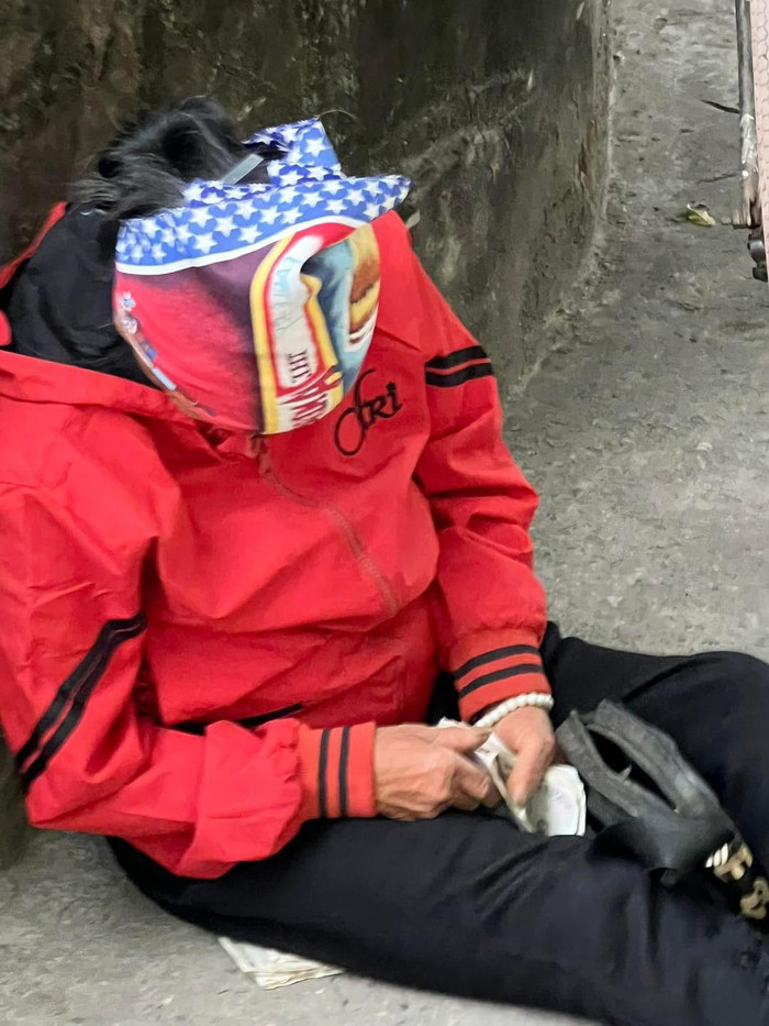 Hình ảnh người phụ nữ ngủ gật bên vệ đường với xấp tiền lẻ còn đang cầm trên tay.