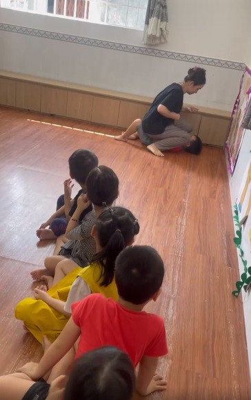 Một bé trai bị cô giáo đè lên người, nhét thức ăn vào miệng