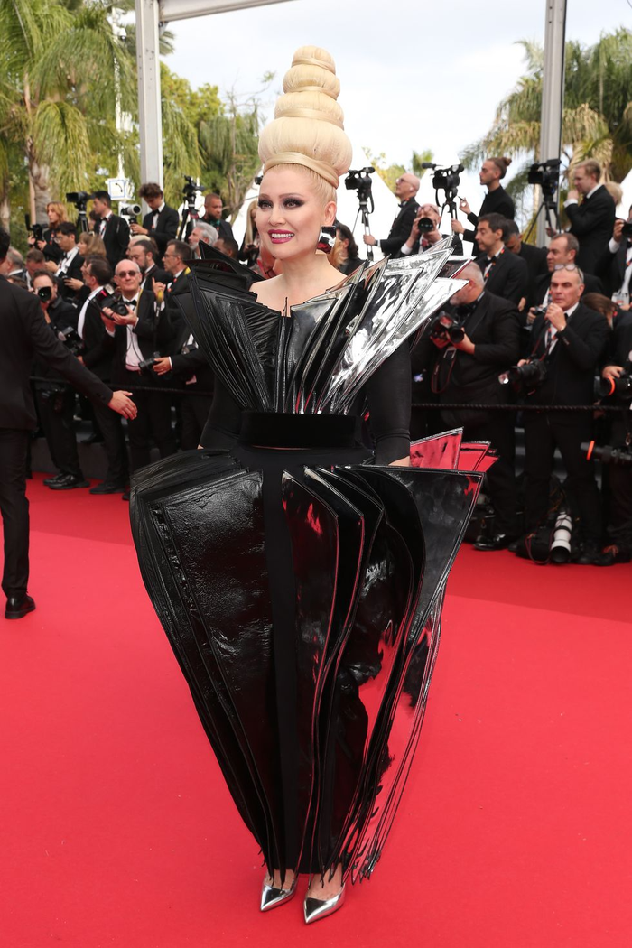 Vẫn như mọi năm, 'dị nhân' thảm đỏ Cannes - Elena Lenina chưa từng ăn mặc 'bình thường' như những người khác. Năm nay, cô diện mẫu tóc như những chiếc bánh bao xếp chồng, đi cùng chiếc váy kỳ quặc được làm kiểu tam giác layer. 