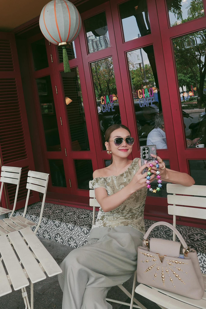 Trong những lần xuống phố hò hẹn, nam nhạc trưởng tích cực lăng xê Thanh Hằng qua nhiều mọi góc máy. Thuận lòng, người đẹp sinh năm 1983 cũng chuẩn bị quần là áo lụa đầy chỉn chu. Bên cạnh tủ váy kiểu cách, cô còn ưa chuộng tạo hình mang tính ứng dụng cao và thuận tiện trong việc di chuyển. Sự kết hợp giữa mẫu quần suông màu ghi và áo trễ vai loang màu được đánh giá cao bởi độ đồng điệu với mẫu túi Louis Vuitton Studded Capucines PM Beige Taurillon Leather.