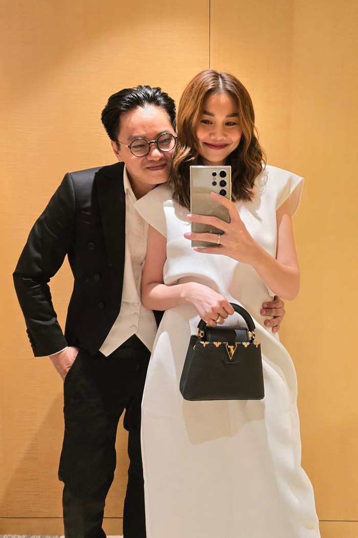 Hậu kết hôn, nàng mẫu có phần ưu ái trang phục có màu sắc trang nhã, đơn giản nhưng không kém phần tôn dáng. Ngày ra thủ đô ủng hộ tinh thần, cô gây ấn tượng với bản phối trắng đen ton sur ton trang phục biểu diễn của ông xã. Mẫu váy nhuộm ngập tông trắng tinh khôi với đường chiết eo tinh tế giúp tôn lên tỉ lệ hình thể của người mặc. Tăng điểm tạo hình, Thanh Hằng chọn cầm tay chiếc túi xách Louis Vuitton Capucines phiên bản giới hạn.