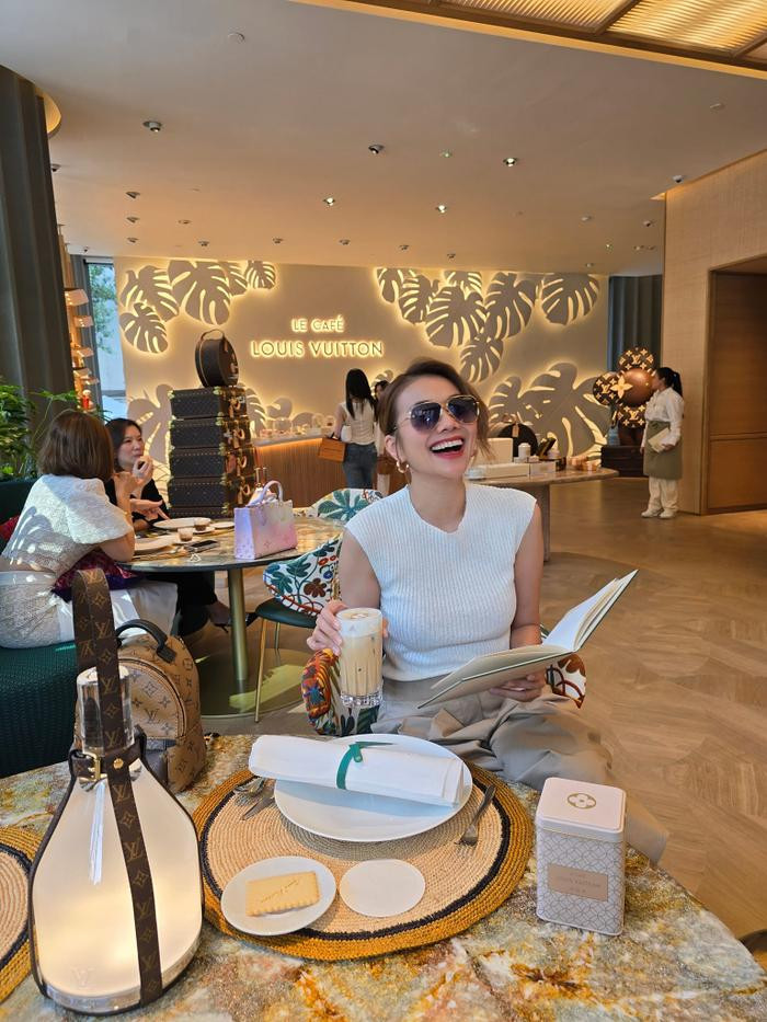 Nối tiếp hình ảnh “chốt đơn” tại gian hàng cao cấp, chân dài Đà Nẵng khiến hội chị em trầm trồ khi khoe cận khoảnh khắc thưởng trà tại không gian Louis Vuitton. Cô ăn vận vô cùng đơn giản với áo trắng cộc tay và quần màu beige. Điểm nhấn của thước ảnh lần này nằm ở bối cảnh được lấy cảm hứng từ thảm thực vật xanh kết hợp nội thất thuộc bộ sưu tập Objets Nomades nổi tiếng của nhà mốt. Được biết, mỗi món trên bàn trà của Thanh Hằng có giá rơi vào khoảng 150.000 - 400.000 đồng.  