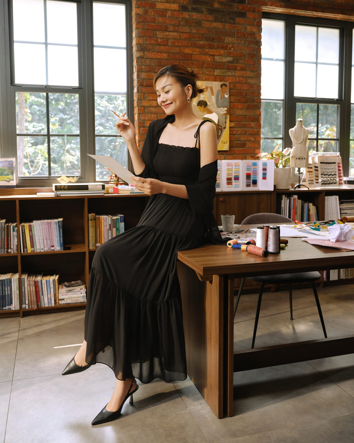 Hưởng ứng tinh thần monochrome, Thanh Hằng khoe sắc vóc trong bộ váy phân tầng, xếp li tông đen. Chất liệu mỏng nhẹ tạo cảm giác thướt tha trong mỗi bước di chuyển. Áo choàng phom ngắn và bản dây nơ mảnh được xem là điểm nhấn cho trang phục. Hoàn thiện tạo hình, cô diện đôi ankle strap mũi nhọn giúp ôm chân.