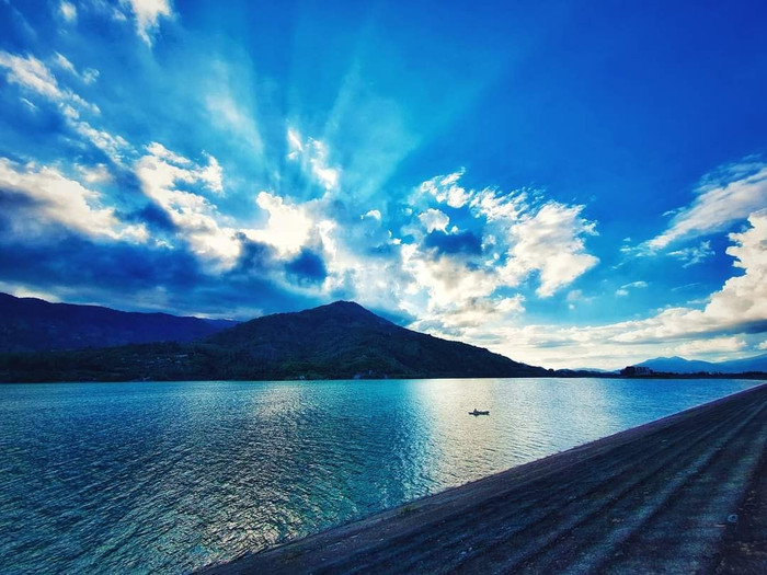 Xung quanh đập Suối Dầu được bao bọc bởi rừng nguyên sinh Hòn Bà xanh mát, điểm xuyết thêm những chiếc thuyền ngoài xa trôi êm đềm giữa bầu trời sương lãng đãng, tạo nên bức tranh thủy mặc đẹp ngây ngất