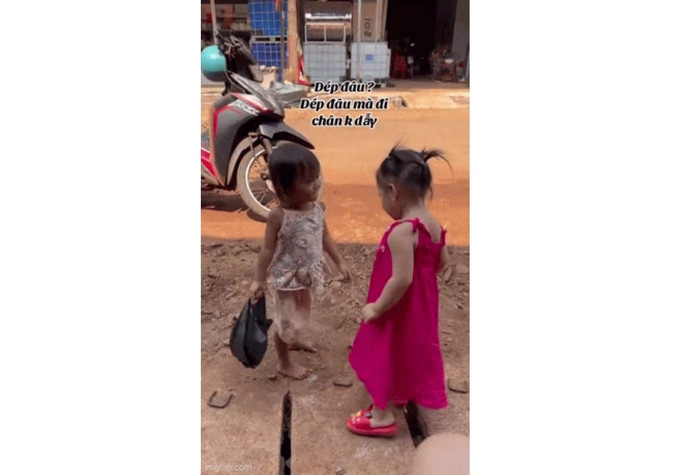 Bé gái váy hồng hỏi han người bạn đi chân đất