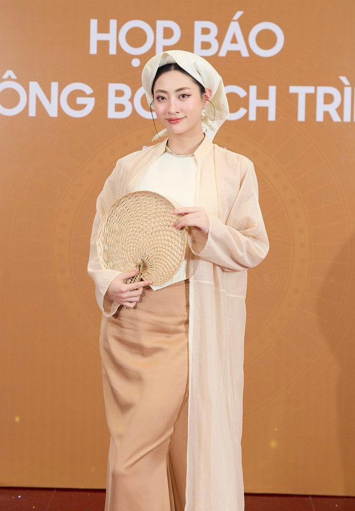 Lương Thùy Linh hoá 'cô tấm' trong bộ trang phục lấy cảm hứng từ áo tứ thân màu nâu nhạt. Nàng hậu còn kết hợp với chiếc quạt bằng tre để tạo điểm nhấn cho lần xuất hiện này.