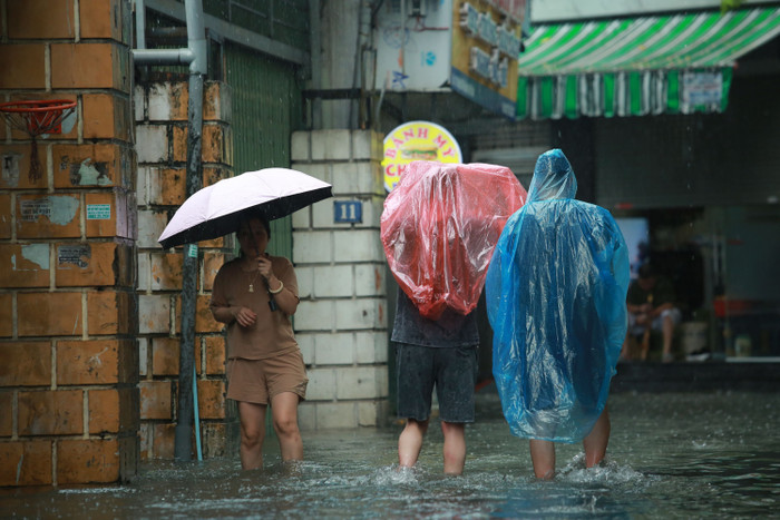 Người dân vất vả đội mưa.