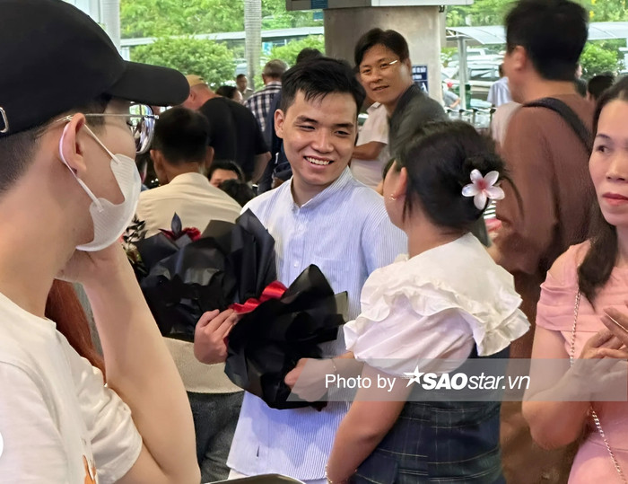 Bạn trai Ý Nhi vẫn vậy. Anh bình dị trong cả cách yêu lẫn gu ăn vận. Theo ghi nhận của SaoStar, Anh Kiệt cùng gia đình bạn gái đã có mặt từ rất sớm tại sân bay Tân Sơn Nhất. Anh Kiệt chọn cho mình chiếc áo sơ mi cổ tàu kẻ sọc, quần pants tông trắng đầy thanh lịch. Thuận tiện cho việc di chuyển, anh đi đôi sneaker có gam trắng đen đan xen. Trên tay chàng sinh viên đại học Kiến Trúc là bó hoa hồng đỏ rực mừng ngày bạn gái về.  