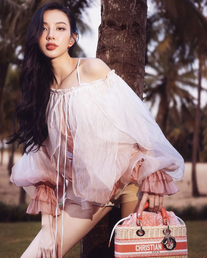 Hưởng ứng không khí lễ hội, Hoa hậu Thùy Tiên thể hiện hình ảnh nàng thơ trong bối cảnh nhuốm màu retro cổ điển. Cô khoe sắc trong mẫu váy công chúa trễ vai, chồng lớp loang phủ sắc hồng cuốn hút đến từ nhà mốt DATT. Thiết kế mang tên Rose blouse được ra mắt giới mộ điệu với giá 8,1 triệu đồng. Tăng điểm, Thùy Tiên sắm dòng túi Dioriviera Lady D - Joy hơn 160 triệu đồng ở phiên bản vừa.