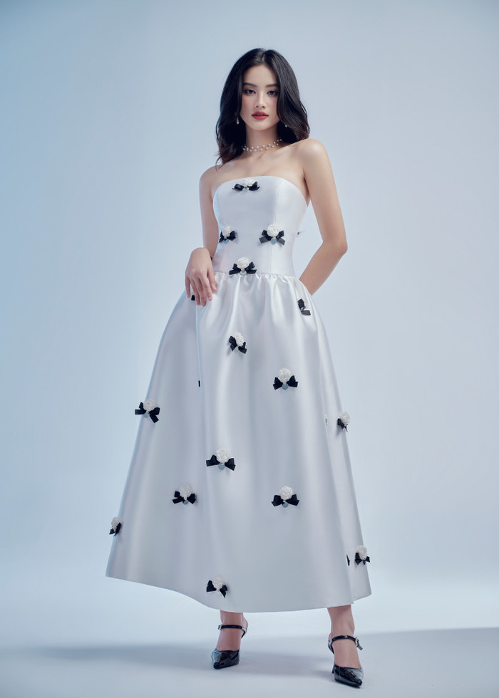 Hơn 1 tuần gần đây, Hoa hậu Ý Nhi khá chăm chỉ 'lăng xê' những mẫu váy dáng dài, che kín vóc dáng. Cô từng khoác lên người mẫu váy cúp ngực, phần tà bung xoè, đính dày đặc hoạ tiết hoa và nơ. Thiết kế này không khiến Hoa hậu Ý Nhi sến sẩm. Ngược lại, nàng hậu Bình Định còn bừng sáng sắc vóc tựa nàng thơ.