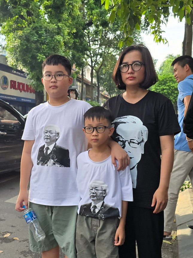 Ba mẹ con chị Nguyễn Thị Thu Ngân (quận Đống Đa, TP Hà Nội) mặc áo có in hình chân dung Tổng Bí thư Nguyễn Phú Trọng xếp hàng chờ vào viếng. Ảnh Trọng Tài