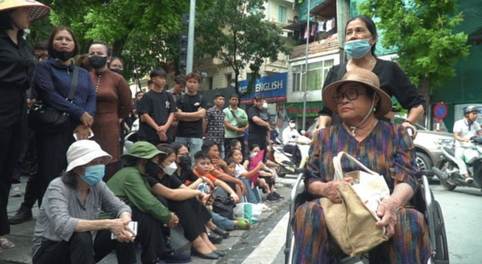 Dù tuổi cao, sức yếu không thể đi lại bình thường, bà Nguyễn Thị Lan (quê Hà Tĩnh) nhờ con cháu đưa đến nhà tang lễ để viếng Tổng Bí thư Nguyễn Phú Trọng. Khi con cháu ngỏ ý đưa về nhà người quen ở gần đó nghỉ ngơi, chờ sắp xếp vào viếng, bà Lan không đồng ý. Tay ôm hộp cơm chuẩn bị sẵn, bà nói sẽ xếp hàng chờ đến khi được vào viếng Tổng Bí thư Nguyễn Phú Trọng.