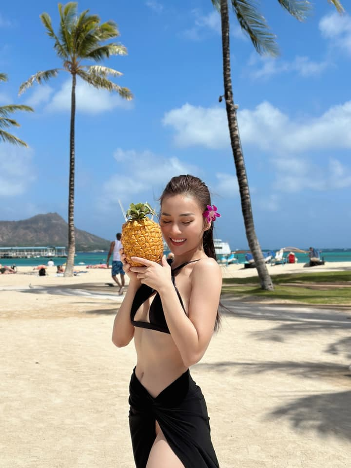 Trong chuyến đi Hawaii cùng ông xã Shark Bình, 'Quỳnh búp bê' thả dáng trên cát với bikini đen xẻ ngực kết hợp váy xẻ tà quyến rũ. 
