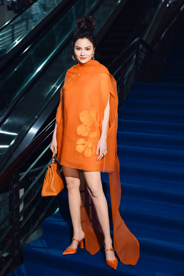 Siêu mẫu Vũ Thu Phương 'ton-sur-ton' từ đầu đến chân. Cô mặc chiếc đầm ngắn chất liệu organza được ẩn thêm hoa phượng bên dưới tạo nên sự cầu kỳ, ấn tượng. Người đẹp còn xách thêm túi Hermes Birkin trị giá trăm triệu. 