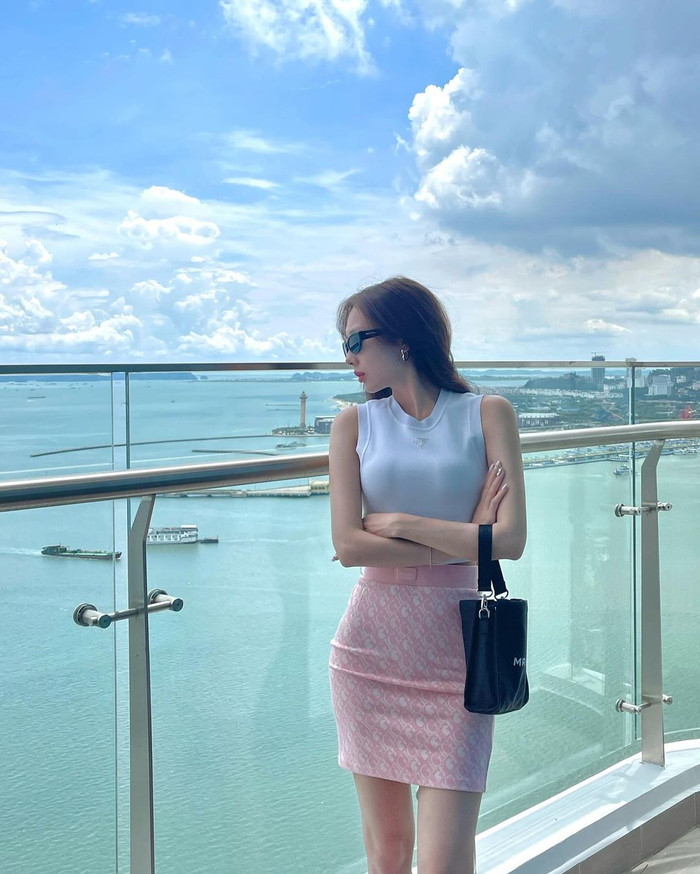 Không những vậy, Yuna Vũ còn theo đuổi phong cách năng động, phóng khoáng. Cô diện mẫu áo croptop ôm sát phối cùng chân váy bút chì màu hồng, hoạ tiết monogram. Để tăng thêm phần ấn tượng, Yuna Vũ phối cùng túi xách và kính mắt màu đen.