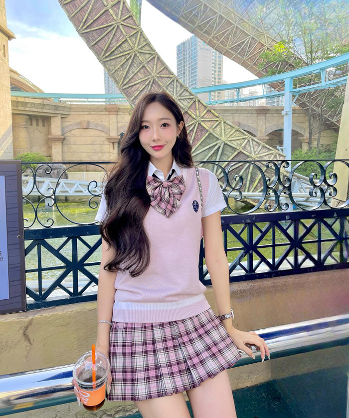 Yuna Vũ đôi lúc theo đuổi phong cách tựa nữ sinh trung học Hàn Quốc. Cô lựa chọn diện nguyên cây trang phục màu hồng tím gồm áo len 3 lỗ, chân váy ngắn khoe đôi chân nuột nà, trắng mịn. Điểm nhấn cho tổng thể bộ trang phục này còn ở chiếc phụ kiện nơ cài cổ bản lớn. Không những vậy, Yuna Vũ còn 'trưng dụng' phong cách trang điểm nhẹ nhàng, đôi môi hồng căng bóng, tôn lên nhan sắc tiên tỷ trong trẻo.