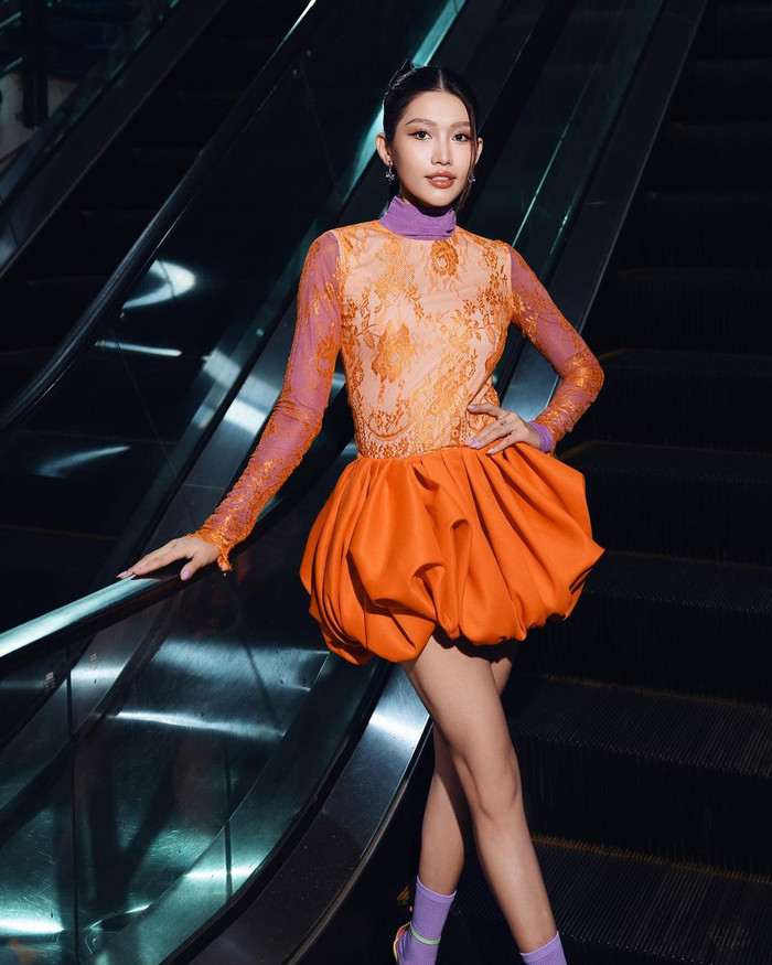 Á hậu Chế Nguyễn Quỳnh Châu màu bắt mắt đến lạ thường. Cô theo 'mốt' Y2K, diện trang phục phối hai tông màu cam - tím. Á hậu Chế Nguyễn Quỳnh Châu khéo léo chọn tông trang điểm đậm theo phong cách Thái Lan. Để tôn lên đường nét sắc sảo của gương mặt, nàng hậu còn 'trưng dụng' kiểu tóc búi gọn gàng ra phía sau.