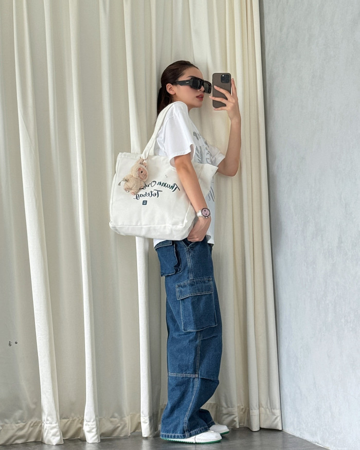 Hoa hậu Kỳ Duyên kết hợp Labubu màu be với chiếc túi tote màu trắng. Về thời trang, cô theo phong cách đường phố với bản phối quần jeans túi hộp cùng áo thun form rộng.