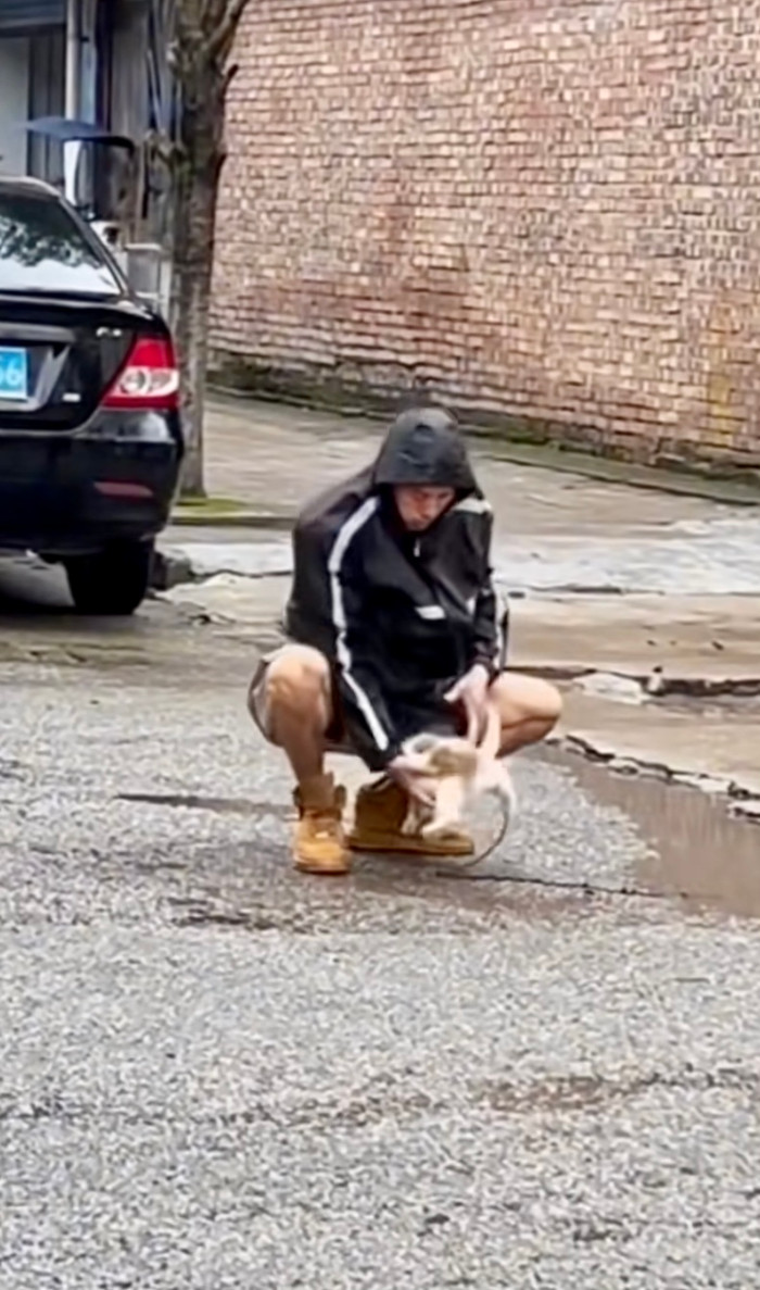 Sau khi đến chỗ khô ráo, chàng trai đã lấy chú chó giấu trong bụng ra khiến người xem thích thú.