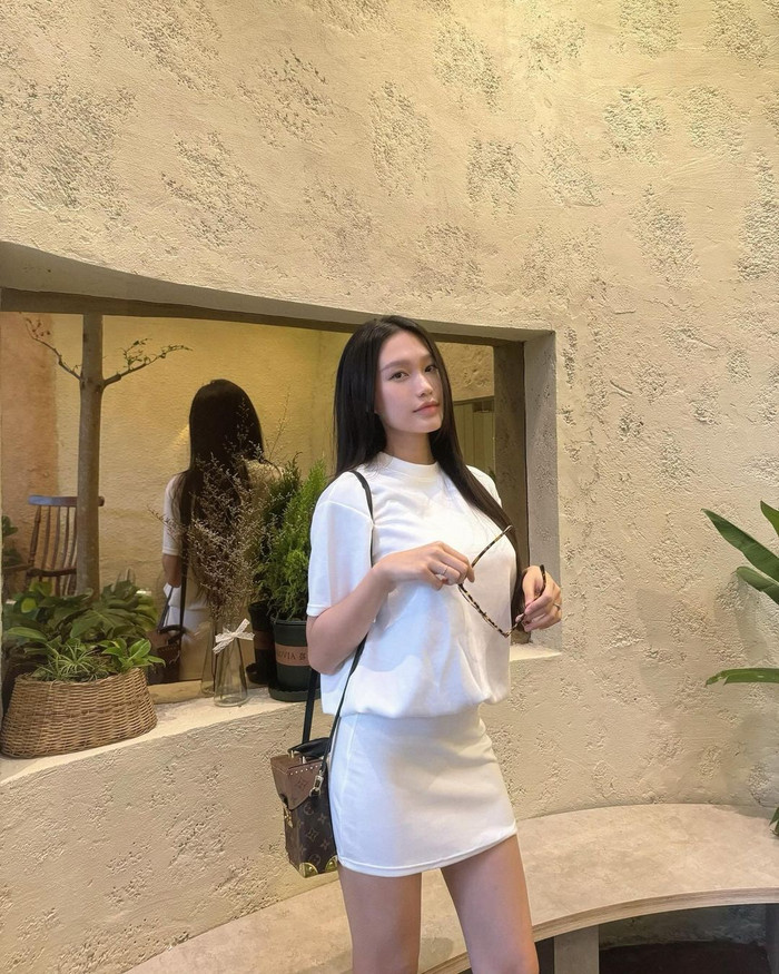 Vợ Đoàn Văn Hậu diện trang phục đơn giản nhưng không kém phần sang trọng. Cô chỉ kết hợp một chiếc áo thun trắng với chân váy ngắn cùng màu, nhưng đã dễ dàng tạo nên vẻ ngoài thanh lịch và trẻ trung.