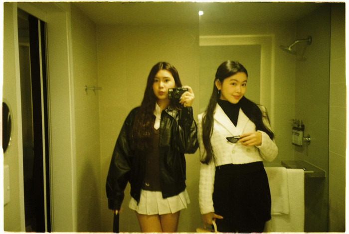 Sự đan xen bảng màu trang phục được hai chị em thể hiện qua từng thước ảnh. Thả dáng trước tấm gương bản lớn, Lọ Lem khoe sắc vóc với thiết kế ôm sát nhuộm tông đen tuyền. Nhấn nhá họa tiết caro, cô chọn mẫu khoác croptop cài khuy đứng phom. Song hành bảng màu trang phục, nàng út Hạt Dẻ cũng lên đồ sành điệu không kém. Sự kết hợp giữa áo khoác da và chân váy tennis tông trắng mang lại vẻ ngoài cá tính nhưng không kém phần năng động cho người mặc.  