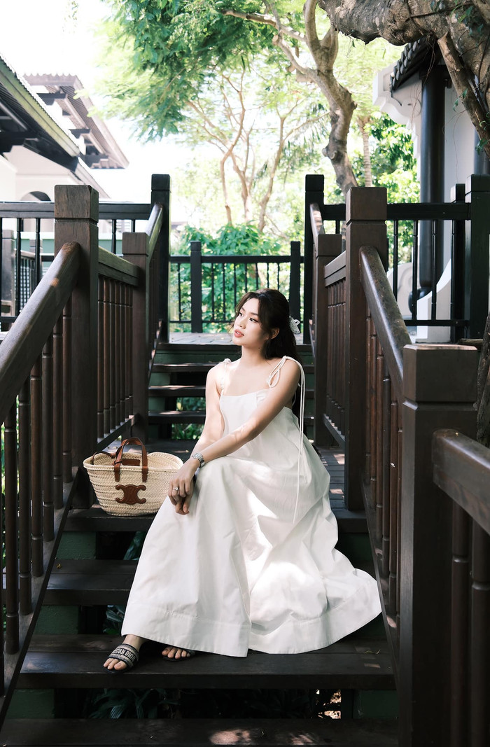 Đỗ Thị Hà diện đầm dài thùng thình, chê đi đôi chân có thương tích do quá trình tập luyện Pickleball. Tuy nhiên, form dáng hai dây của thiết kế này phần nào giúp nàng hậu xứ Thanh khoe khéo 'bờ vai móc áo' cùng phần xương quai xanh thu hút. Tận dụng gương mặt mềm mại, nhan sắc trong trẻo, Đỗ Thị Hà khéo léo sử dụng phong cách trang điểm nhẹ nhàng để tôn lên ưu điểm này. Lần xuất hiện của cựu Hoa hậu Việt Nam còn thêm phần 'chanh xả' với hàng loạt những món phụ kiện hàng hiệu như túi xách, dép lê.