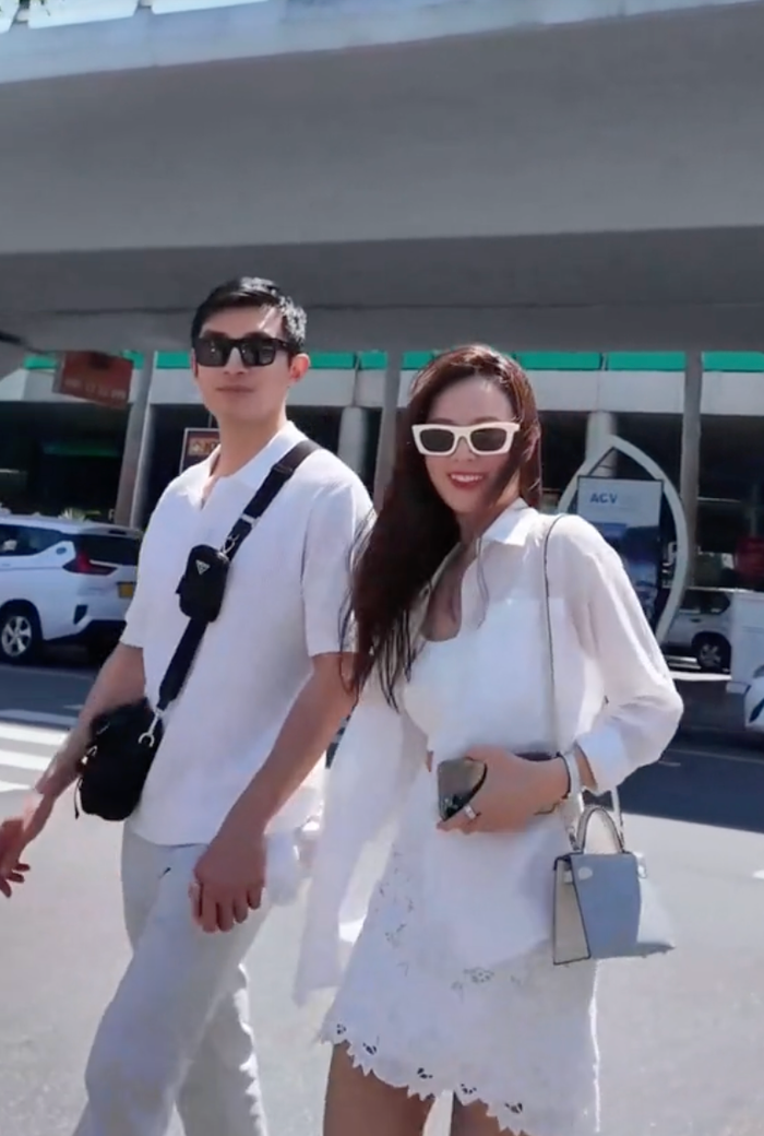 Midu được chồng nắm chặt tay khi di chuyển ra sân bay trong chuyến công tác mới nhất. Ảnh: FBNV