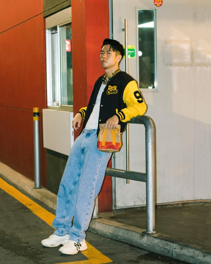 Đôi lúc, Michael Trương còn theo đuổi phong cách cá tính, mang hơi hướng street style. Tổng thể tạo hình của nam người mẫu là sự hoà quyện của quần jean dáng rộng, áo ba lỗ ôm sát, giày sneaker cùng chiếc áo khoác bomber màu vàng - đen tạo điểm nhấn.