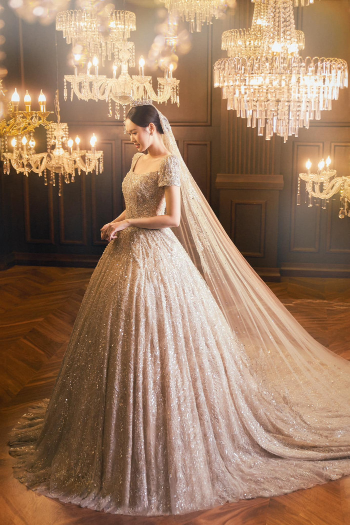 Bên cạnh đó, chiếc váy cưới trở nên đặc biệt hơn khi được đính kết hàng trăm  viên đá Swarovski được nhập khẩu từ Áo, làm nổi bật từng chuyển động nhẹ nhàng của cô dâu, hòa quyện với các lớp lưới mỏng nhẹ bên trong, tạo nên kiểu dáng ballgown hoàn hảo và đầy quyến rũ.