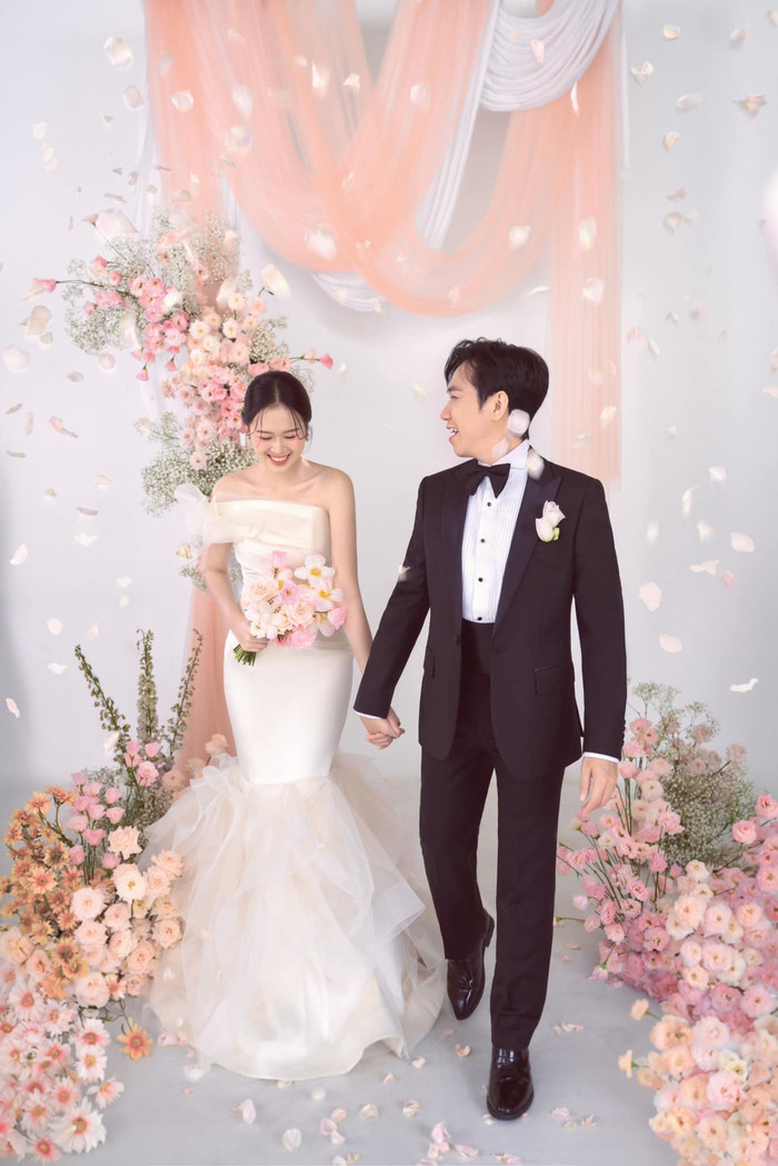 Chiếc váy cưới thứ hai cô dâu Anh Phạm chọn diện trong ngày cưới là một chiếc đầm lệch vai đuôi cá khéo léo tôn lên các đường cong quyến rũ. Những nếp xếp kết hợp cùng phần lưới voan cứng làm nổi bật sự nhẹ nhàng và uyển chuyển. 