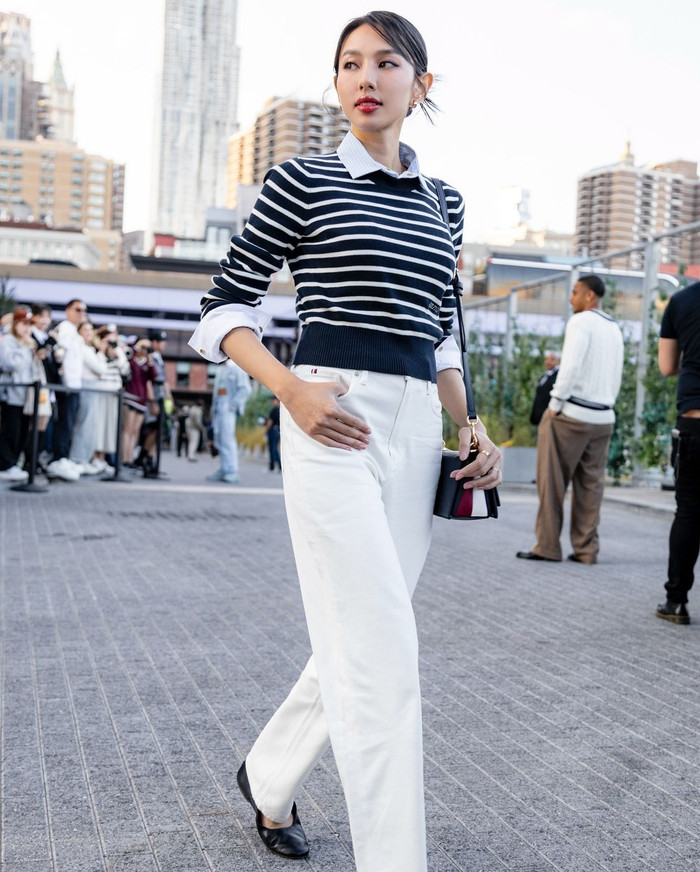 Đi theo tôn chỉ của thương hiệu, Hoa hậu Thùy Tiên lựa chọn bản phối đạt đủ 3 yếu tố thanh lịch, thời thượng và phong cách. Người đẹp sinh năm 1998 diện áo sweater sọc ngang xanh than và trousers ống rộng tông trắng. Tăng độ thời thượng, cô lựa chọn mẫu túi đeo chéo lồng chữ biểu tượng TH Monogram Crossover và đôi giày Mary Jane Ballerinas phiên bản da thuộc. Chỉ sau ít giờ lên sóng, tạo hình của Hoa hậu Thùy Tiên lại được đặt lên bàn cân so sánh với chị cả BLACKPINK - Jisoo.  