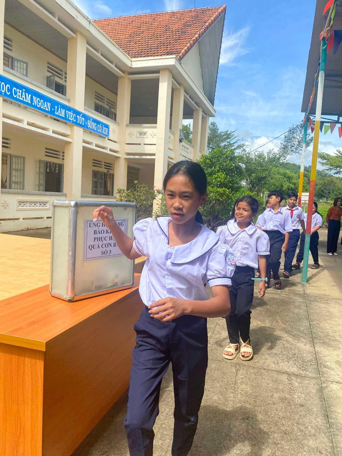 Các em học sinh xếp hàng gửi những món quà nhỏ, quyên góp đến bà con vùng bão lũ. Ảnh: Trường Tiểu học Bằng Lăng