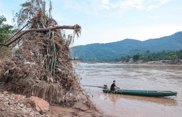Đường vào bản đã bị sạt lở và người dân chỉ có thể di chuyển bằng thuyền máy qua sông Chảy, đối mặt với nhiều nguy cơ mất an toàn do dòng nước vẫn chảy mạnh. Ảnh: TTXVN.