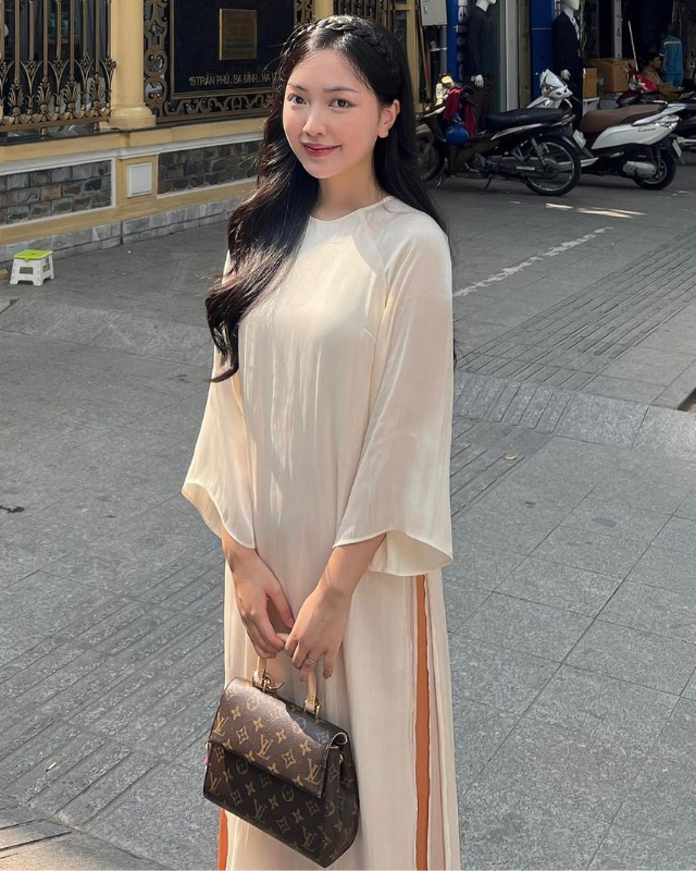 Trong một lần dạo phố nhân dịp Lễ đặc biệt, Mai Hà Trang - vợ Hà Đức Chinh khoác lên người mẫu áo dài phối hai màu be và cam đất tôn lên nhan sắc trong trẻo, thu hút. Để tổng thể thêm phần ấn tượng, có điểm nhấn, nàng hot girl phối cùng mẫu túi xách đến từ thương hiệu đình đám nước Pháp. Thiết kế này mang form hình chữ nhật, có nắp gập và mang hoạ tiết monogram. Nó được bán với mức giá khoảng 60 triệu đồng.