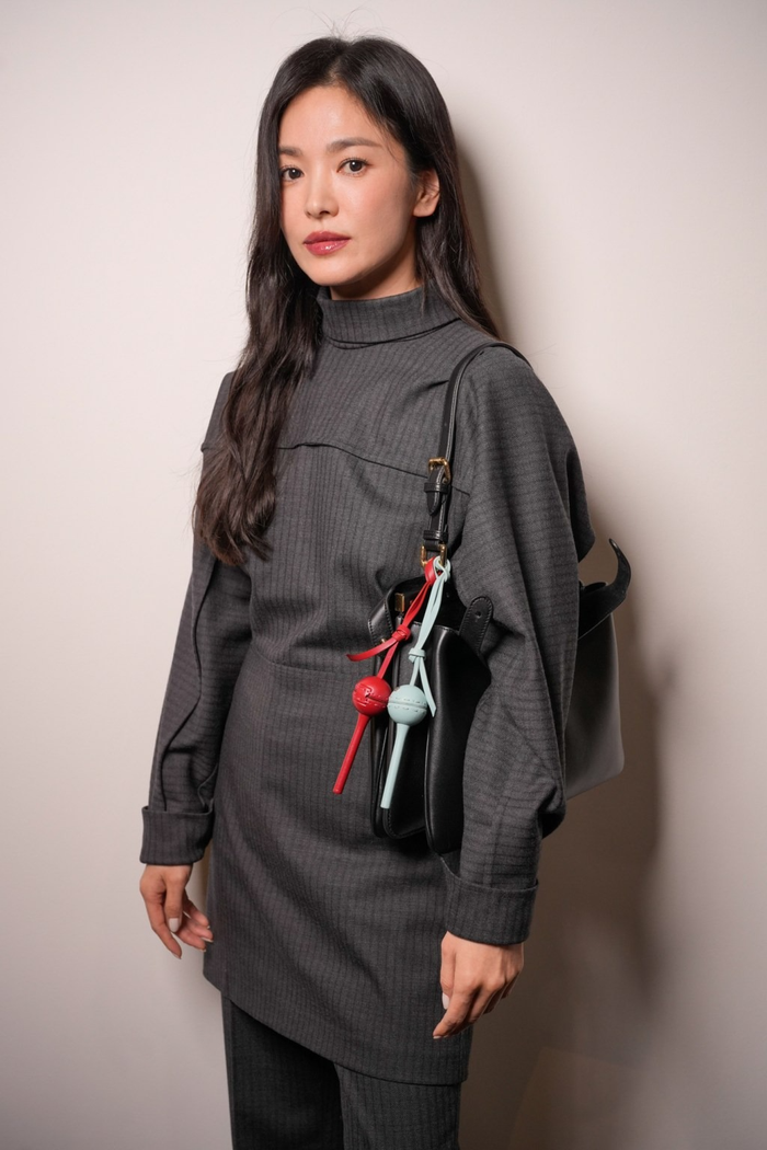 Mỹ nhân sinh năm 1981 mẫu áo dài tay cổ lọ có độ dài qua mông với đường may tỉ mỉ phối cùng mẫu quần dài 'ton-sur-ton'. Trên vai Song Hye Kyo đeo thêm túi da được trang trí phụ kiện hình kẹo mút. Không cần để lộ chút 'da thịt', nữ diễn viên vẫn để lại khí chất cực kỳ thu hút trên thảm đỏ. 