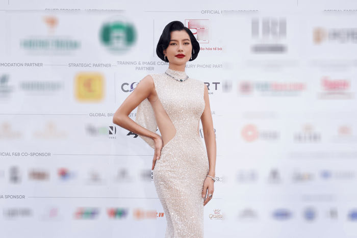 Á hậu Hoàng Nhung đẹp quyền lực với tóc ngắn kèm son đỏ. Chân dài 1m79 khoác trên người mẫu đầm sequins lấp lánh, khoét hai bên eo giúp khéo khoe ba vòng chuẩn chỉnh. Hình ảnh của mỹ nhân quê Hà Nội được nhận xét giống những quý cô có xuất thân vương giả. 