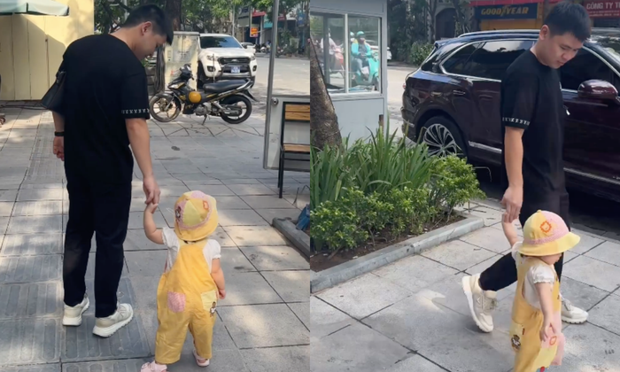Chồng Đỗ Mỹ Linh nắm tay con gái Tuệ An bước đi trên phố. 