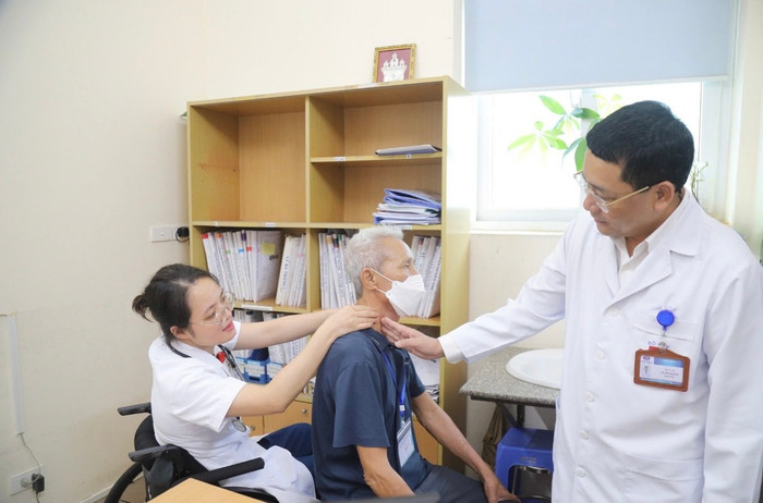 Bác sĩ Hoàng Minh Lý ngồi xe lăn khám bệnh cho bệnh nhân (Ảnh: Thái Hà). 