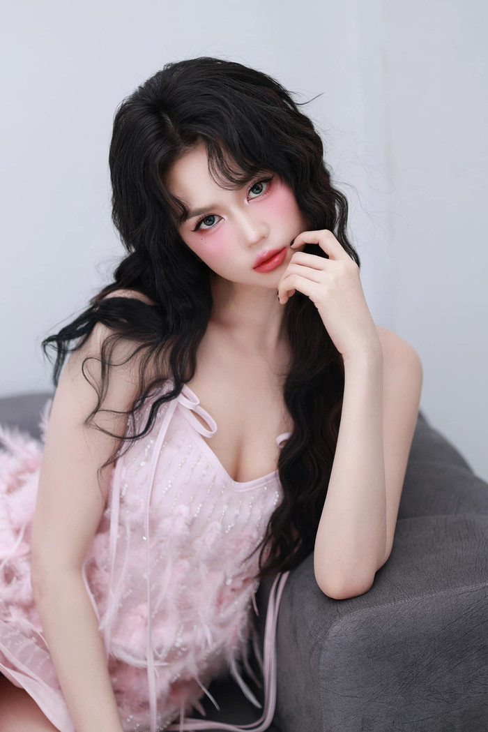 Việc cắt tóc tém sát gương mặt mang lại không ít những bất lợi cho Ngọc Trinh khi thực hiện những bộ ảnh thời trang. Cô liên tục phải đội tóc giả để phù hợp với từng concept. Trong bộ ảnh mới nhất, Ngọc Trinh gây chú ý với nhan sắc trẻ trung, thu hút khi khoác lên người mẫu váy hai dây mảnh, đính lông vũ. Thiết kế này còn được khoét sâu, để lộ hờ hững đường chân ngực nóng bỏng. Không những vậy, 'người đẹo Trà Vinh' còn trưng dụng phong cách trang điểm nhẹ nhàng, nhấn nhá rõ nét phần má hồng hào sát lên bầu mắt dưới. Giao diện của Ngọc Trinh khiến người hâm mộ liên tưởng đến hình ảnh nàng búp bê barbie.